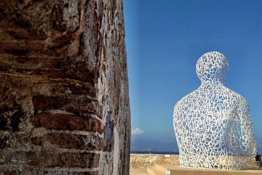 A stone wall and a large white sculpture. 2