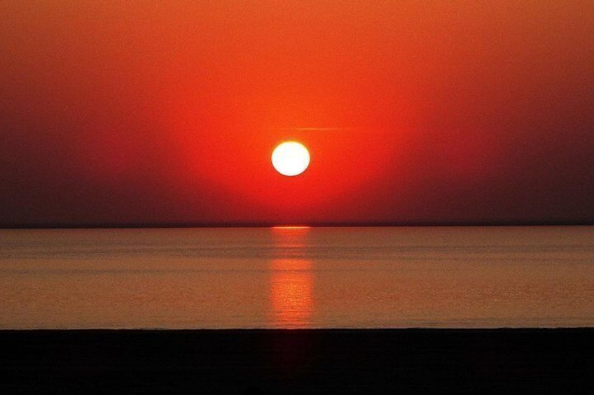 Ein Sonnenuntergang über ruhigem Gewässer, die Sonnenreflexion spiegelnd. 3