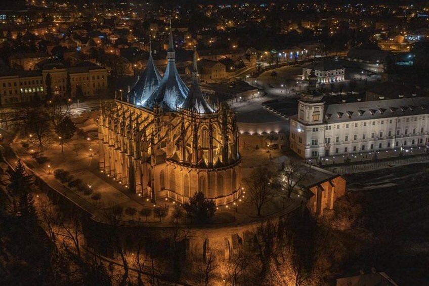 Une cathédrale à trois flèches, entourée d’un paysage urbain illuminé par les lumières de la nuit. 2