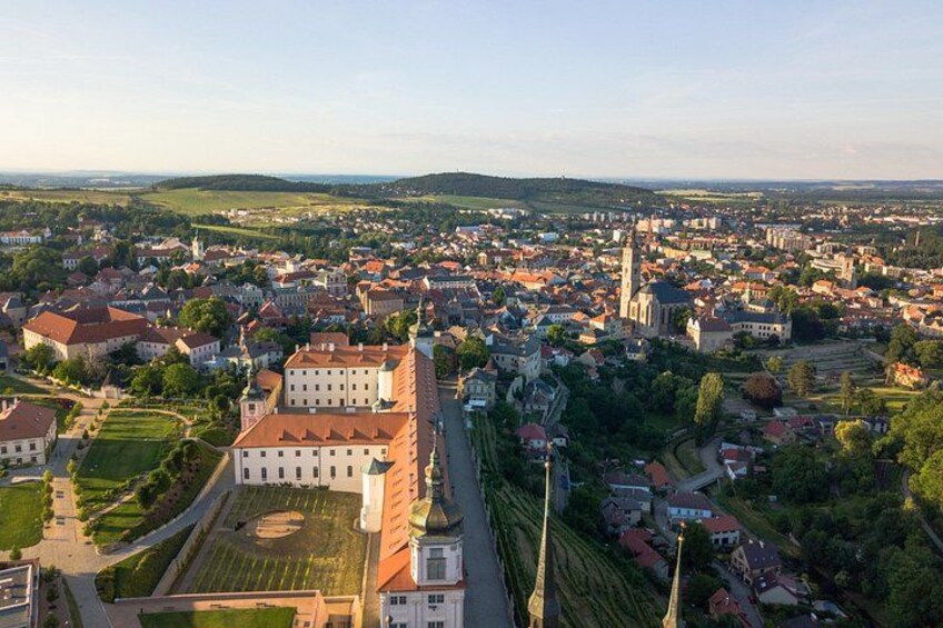 Une vue aérienne d’une ville avec un château imposant, une église et une végétation luxuriante environnante. 3