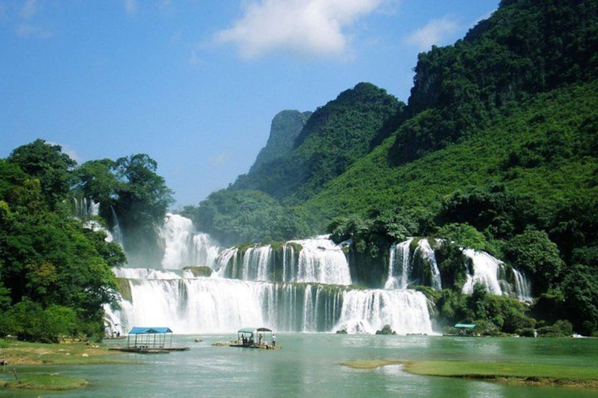 A waterfall cascading into a river surrounded by lush greenery and hills. 1