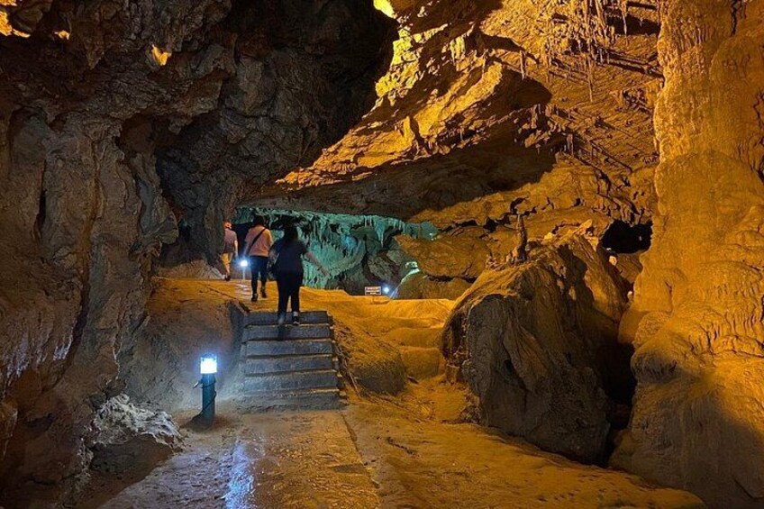 A cave with a staircase leading to a higher level, illuminated by artificial lights. 4