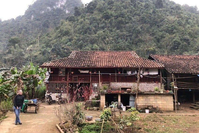 A rural house with a tiled roof, surrounded by vegetation and a hilly landscape. 5