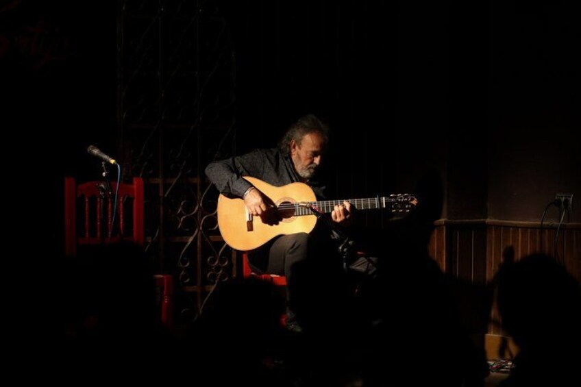 A person playing an acoustic guitar on a stage with a microphone. 3
