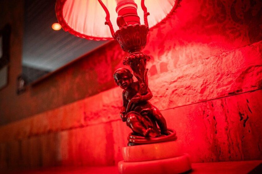 A red-lit statue of a child with a lamp. 5