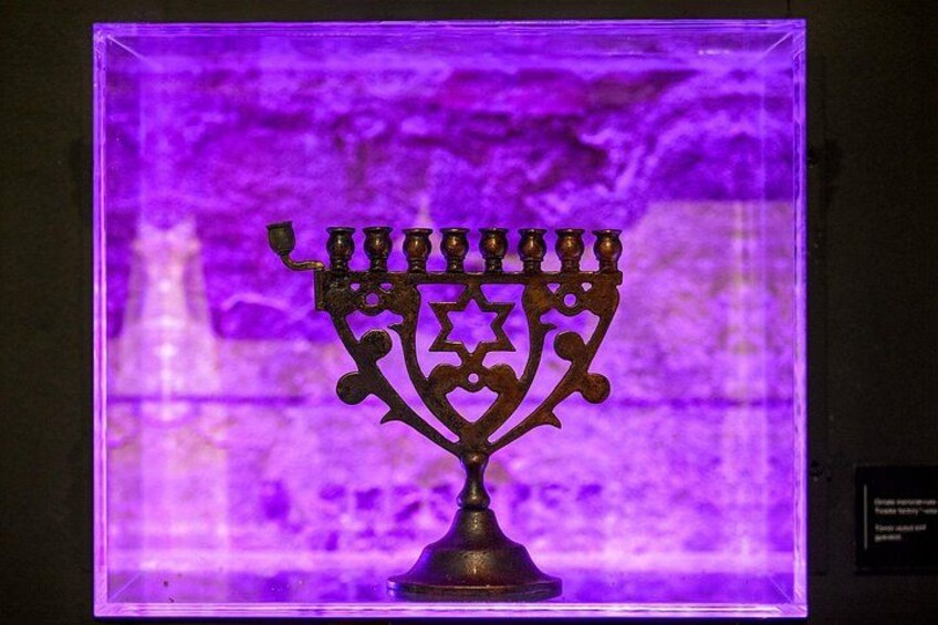 A menorah with a star-shaped top, displayed in a clear case with a purple background. 4