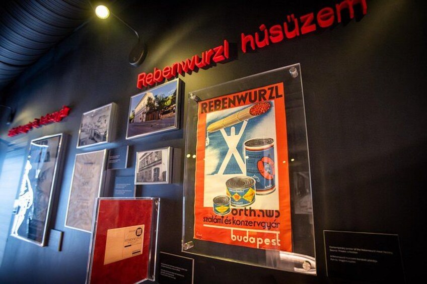 A wall with various historical posters and photographs, including one promoting canned food. 3
