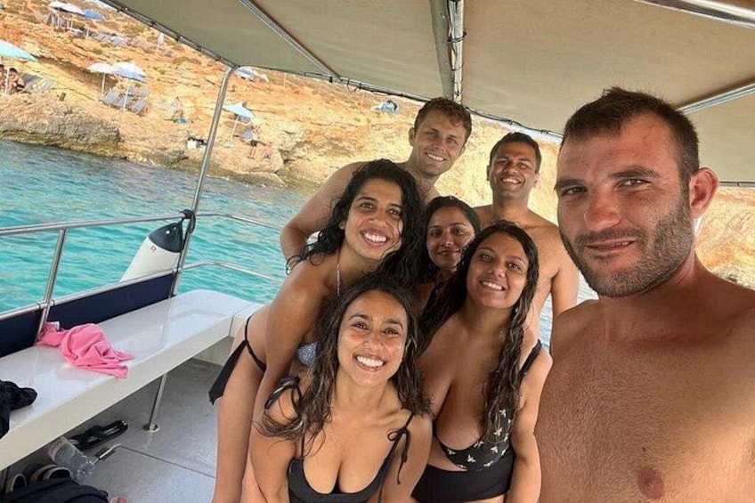 A group of people on a boat near a rocky shore with clear water. 4