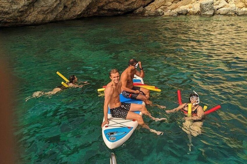 People snorkeling in clear water with rocks in the background. 3