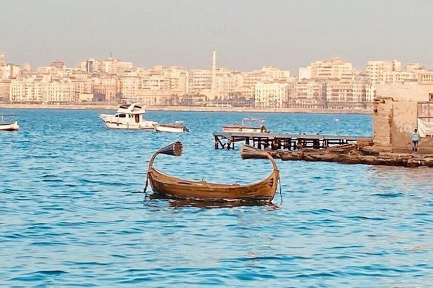 A wooden boat in calm water, a city skyline in the background, and a pier with a person standing. 4