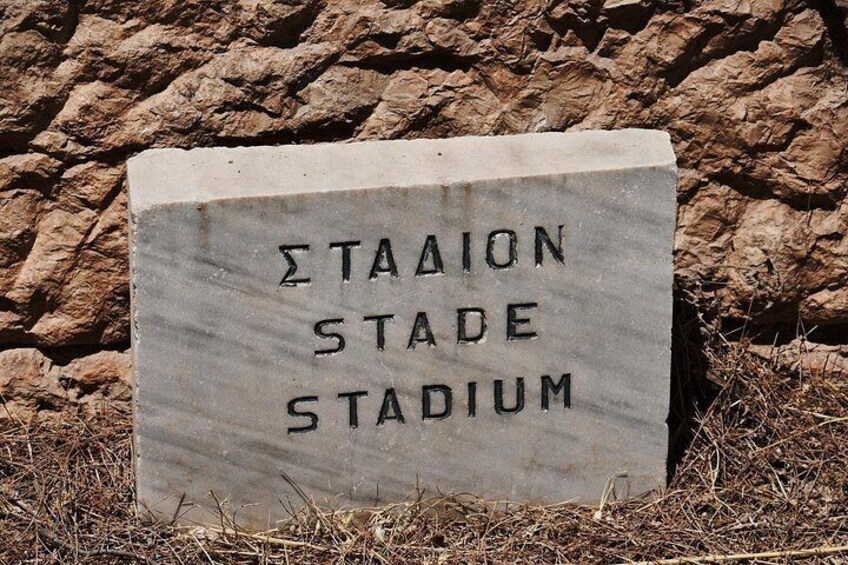A stone sign with the words 'ΣΤΑΑΙΩΝ ΣΤΑΔΕ ΣΤΑΔΙΟΜ' which translates to 'Stade Stadium' in English. 1