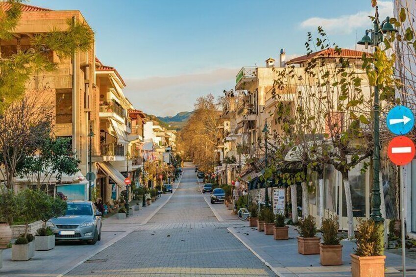 A street lined with buildings, potted plants, and cars. 4