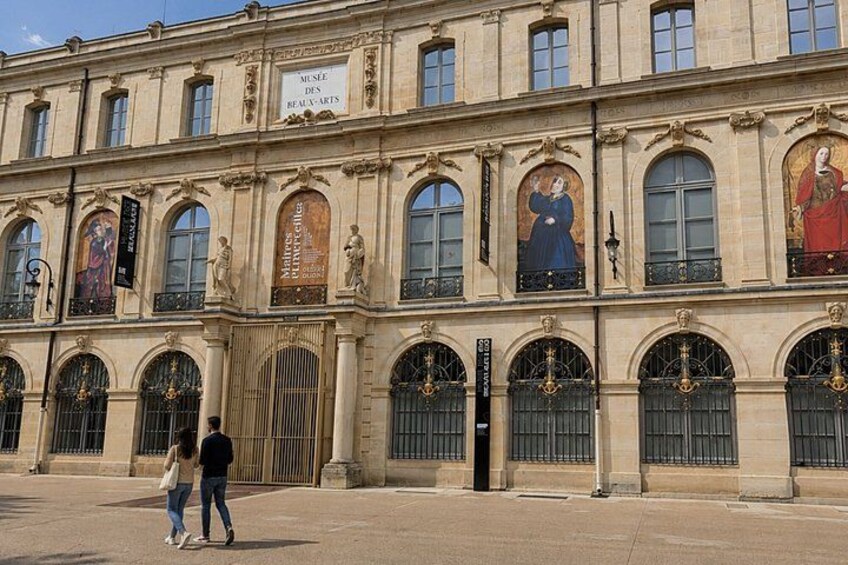A historic building with classical architecture, featuring arched windows and statues. 3