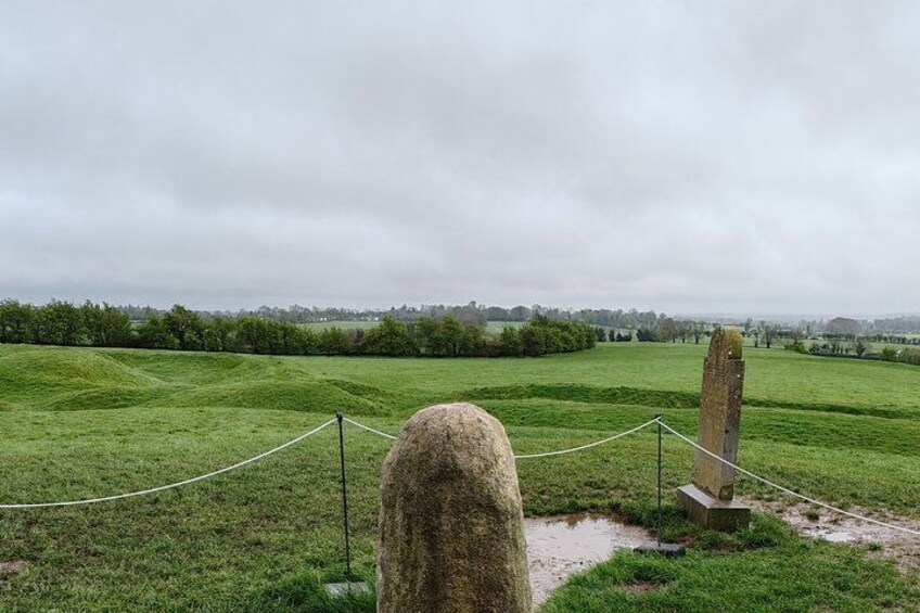 A stone monument in a grassy field with a rope barrier. 5