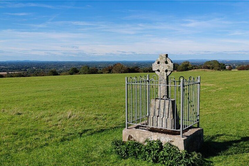 A stone cross with a fence in a grassy field. 4