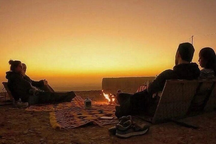 People sitting on chairs facing a sunset. 2
