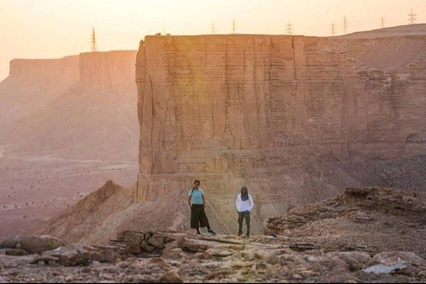 A large rock formation with two people walking near it. 5