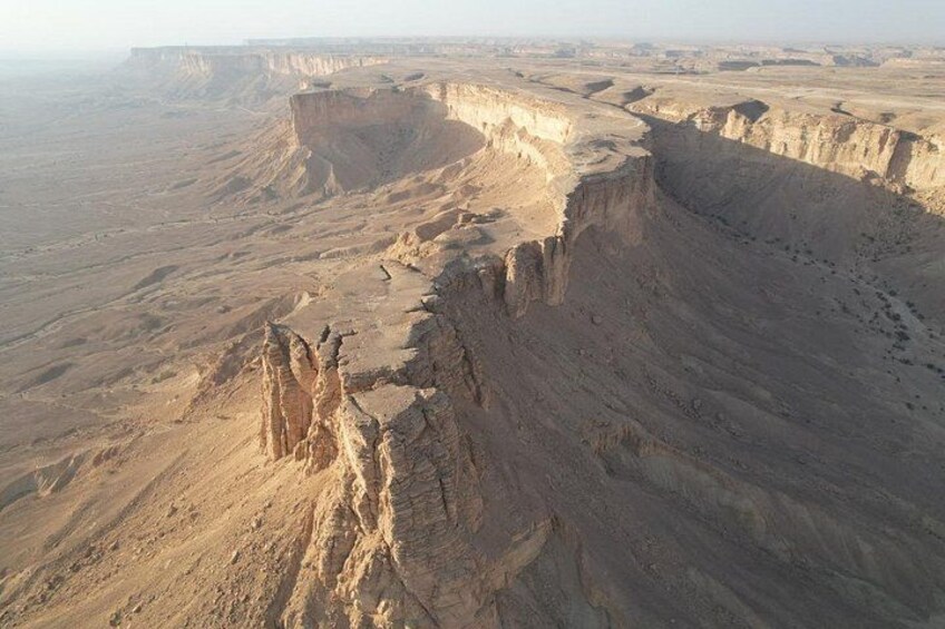 A vast desert landscape with prominent cliffs and a flat terrain. 3