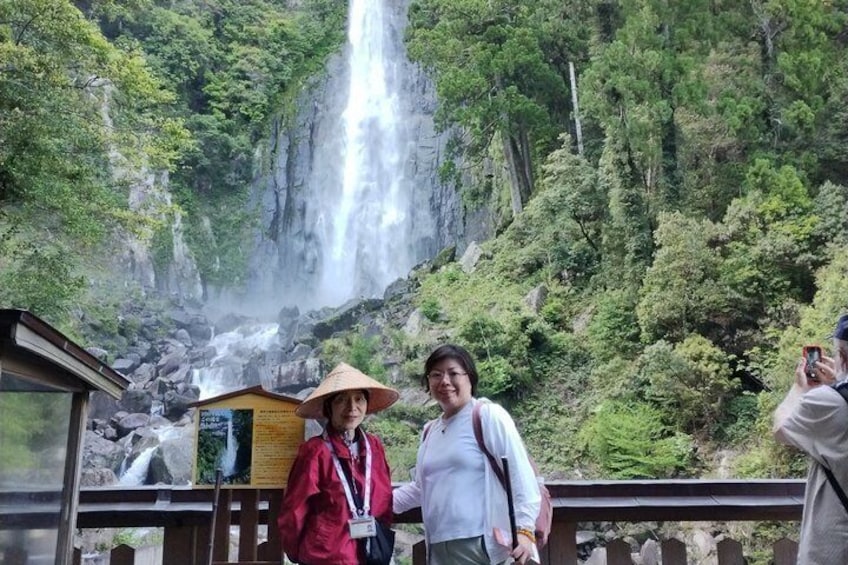 A waterfall, a wooden observation deck, and two people wearing hats. 5