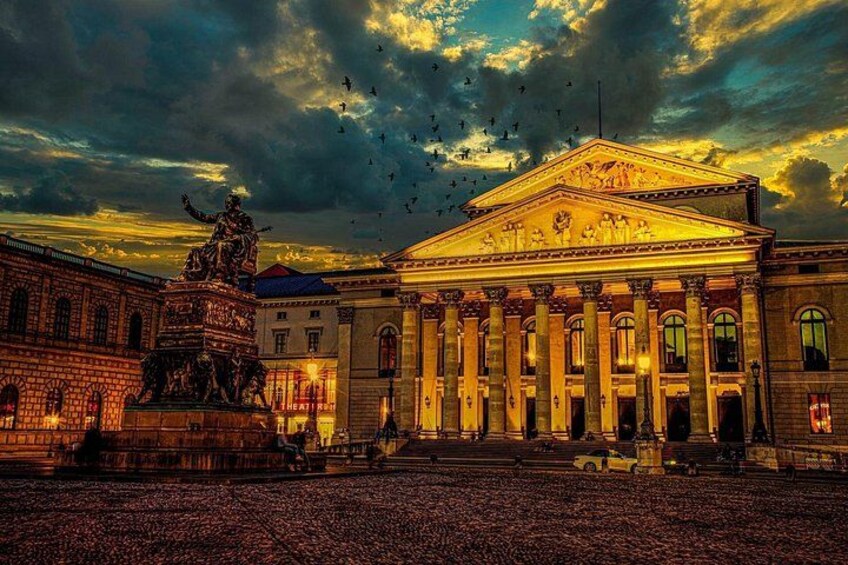 A grand building with classical architecture, a large statue in front, and a dramatic sky. 1