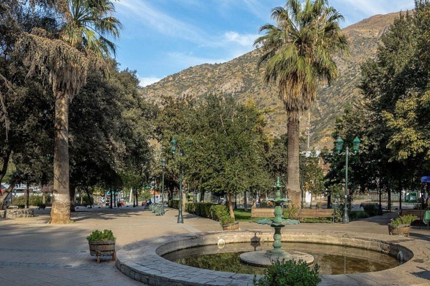 A park with palm trees, a fountain, and a mountain in the background. 2
