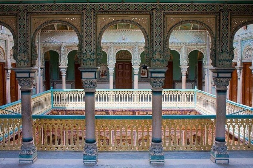 Ein kunstvoller Innenhof mit Bögen, Säulen und einer verzierten Brüstung. 4