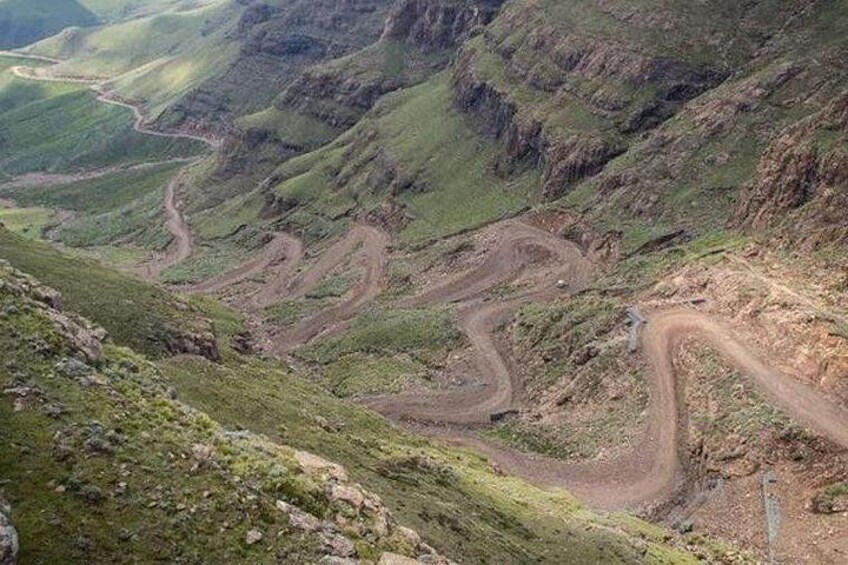 Een kronkelende bergweg, omringd door steile kliffen en schaarse begroeiing. 5