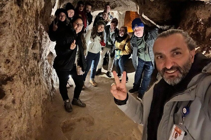 A group of people inside a cave with rocky walls and a dirt floor. 3