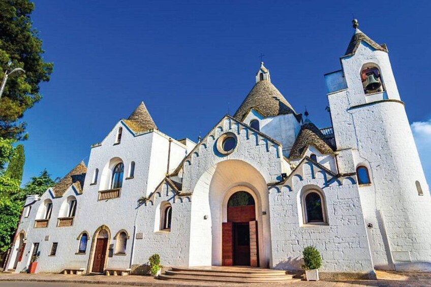 Una chiesa bianca con un campanile, finestre ad arco e una porta rossa. 4