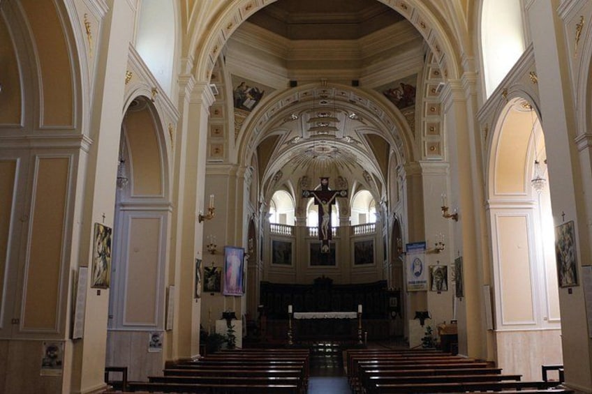 Interno di una chiesa con soffitti a volta, bancali di legno e un altare centrale. 3