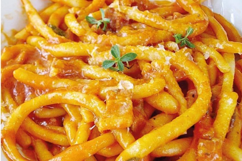 A close-up of spaghetti with a tomato-based sauce, garnished with herbs and grated cheese. 3