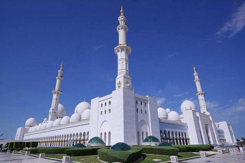 En stor, hvid moské med flere kupler og minareter, omgivet af velholdte haver. 1