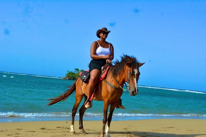 Une personne à cheval sur une plage, avec l’océan en arrière-plan. 1