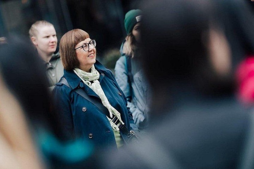 A person in a blue coat and scarf standing in a crowd. 2