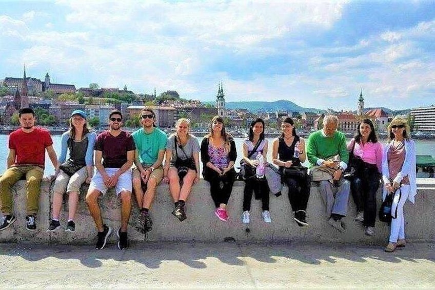 A group of people sitting on a ledge with a cityscape in the background. 4