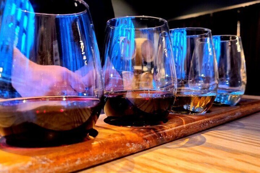 A wooden tray with several wine glasses, some filled with red wine and others empty. 5