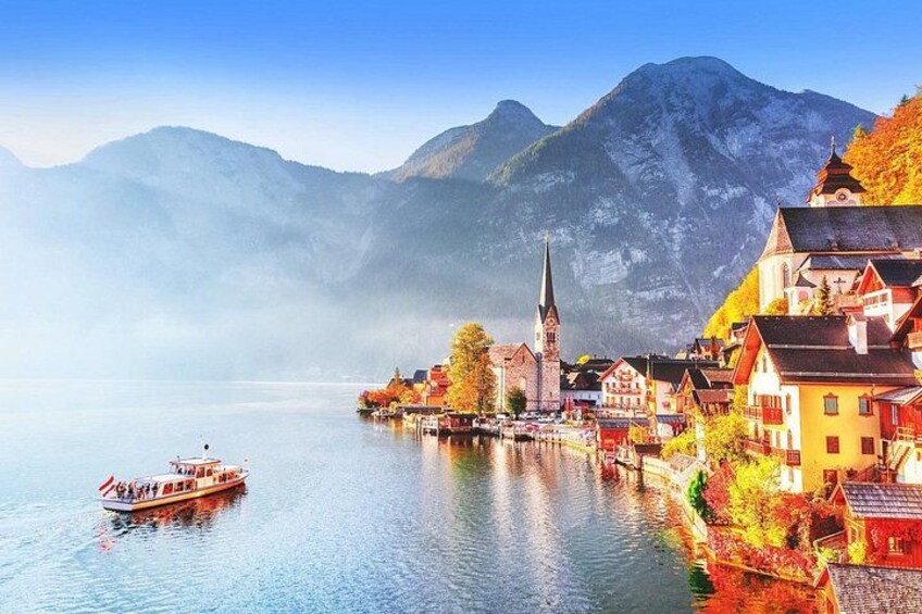 A lakeside town with colorful buildings, a church, and mountains in the background. 1