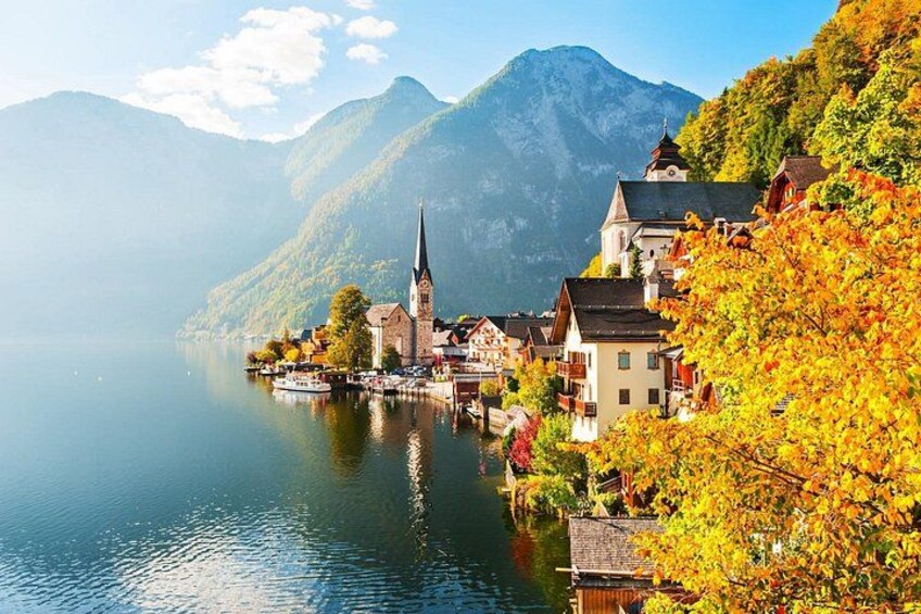 A lakeside village with a church, houses, and autumn foliage. 2