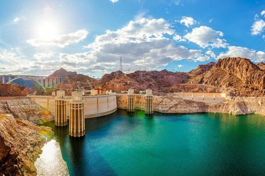 Una represa hidroeléctrica con múltiples compuertas, un puente y un paisaje montañoso. 3