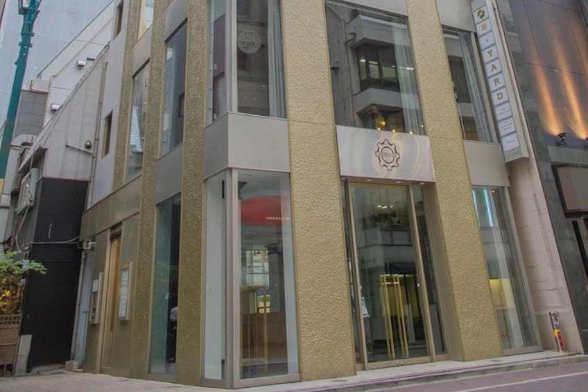 Un edificio moderno con fachada color beige, amplias ventanas de vidrio y un logotipo destacado en la entrada. 5