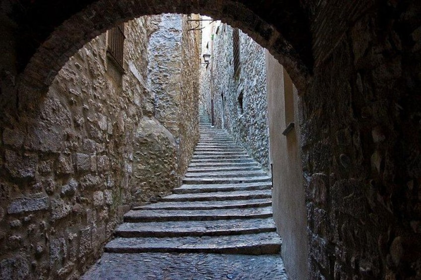 A stone staircase in a narrow alleyway with arched ceilings. 1