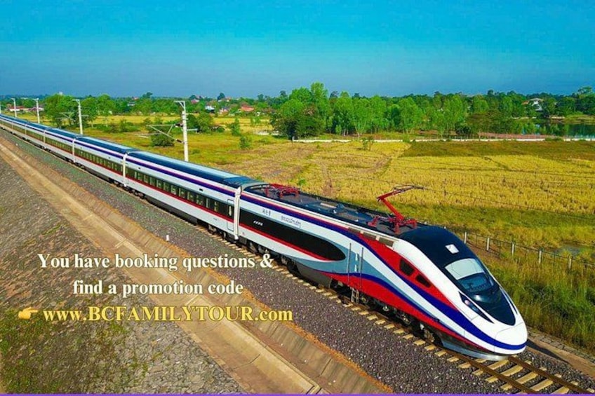 A high-speed train on tracks with a rural landscape in the background. 1
