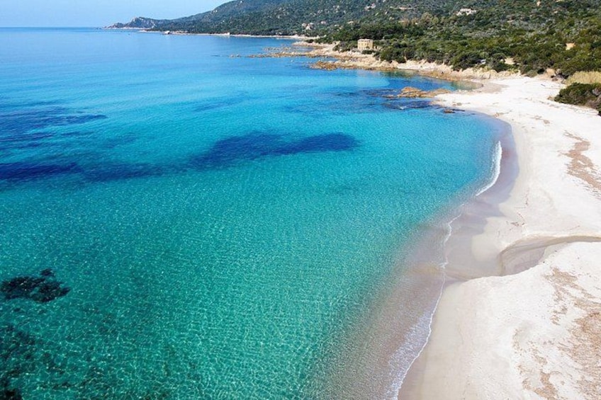 A beach with clear turquoise water, sandy shore, and a hilly landscape in the background. 1