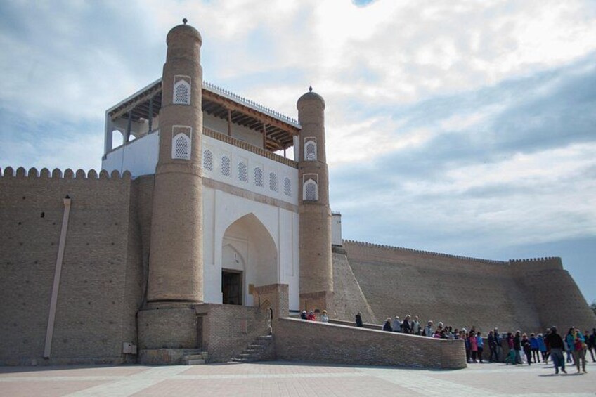A historic fort with a large arched entrance, two prominent towers, and a crowd of people. 3