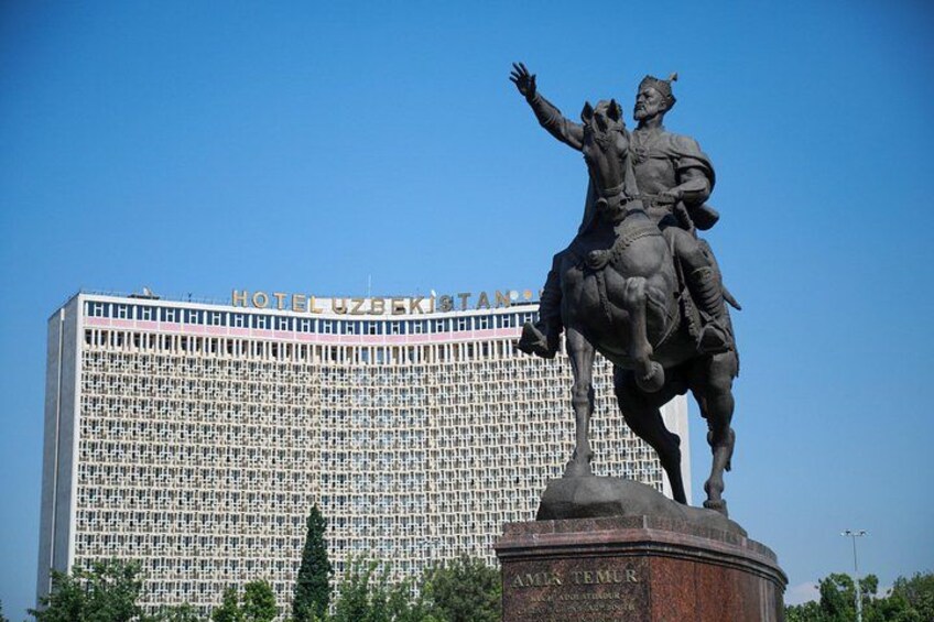 A statue of a historical figure on horseback in front of a large building with a grid-like facade. 2