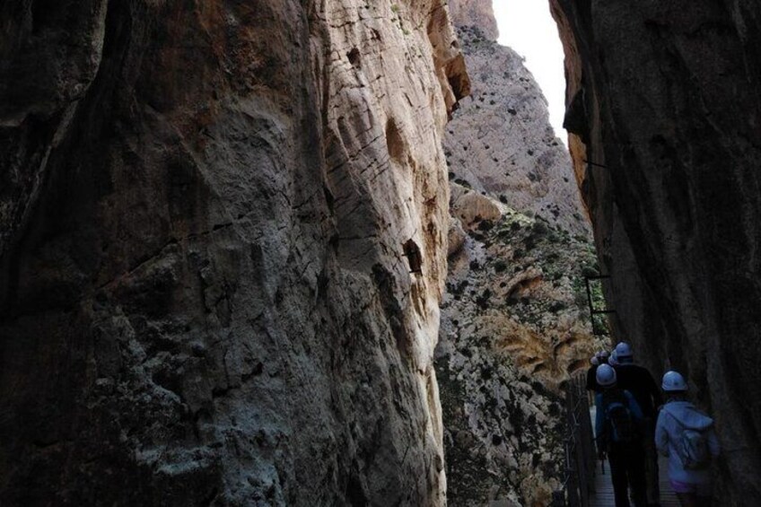 A narrow canyon with rocky walls and a group of hikers. 3