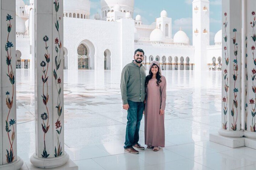 A couple standing in a white architectural courtyard with columns and arches. 4
