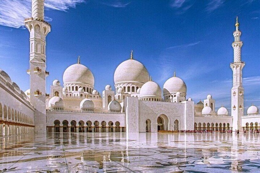 A mosque with large domes and minarets, a reflective courtyard, and a clear blue sky. 5