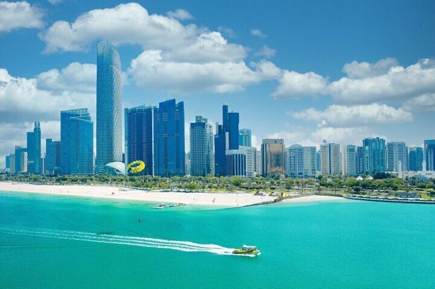 A coastal cityscape with a prominent skyscraper, a beach, and a clear blue sea. 2