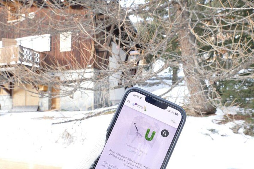 Ein Smartphone zeigt eine Karte mit einem grünen 'U'-Symbol, einen Holzzaun und kahl stehende Bäume in einer verschneiten Landschaft. 1